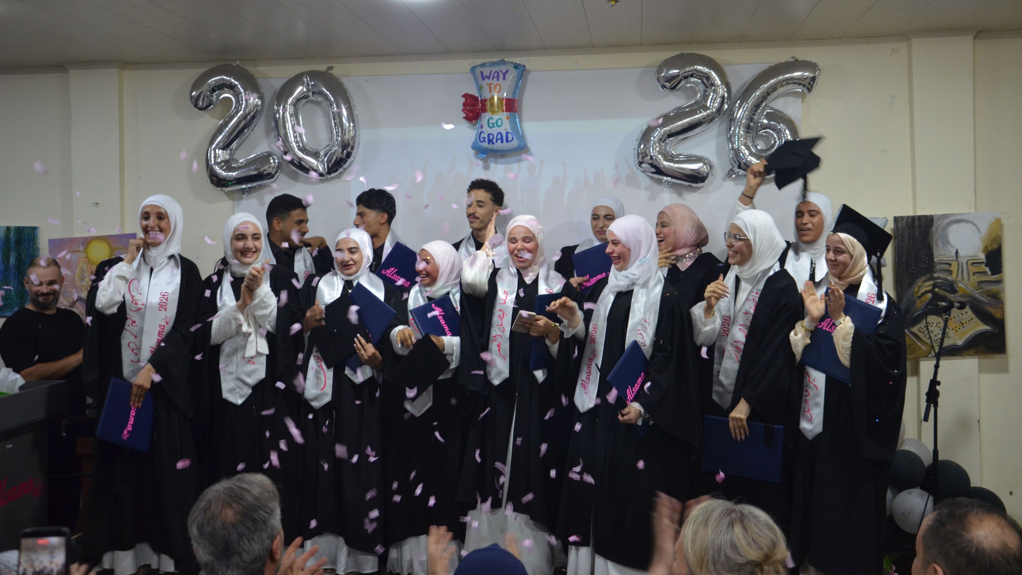 Graduates celebrating on stage as confetti falls